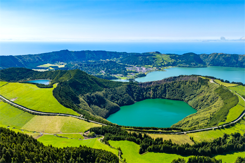 Uitzicht op São Miguel op de Azoren met groene heuvels, een blauw kratermeer en weelderige natuur rondom het water.
